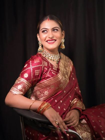 A joyful portrait of a bride in a rich maroon saree, her smile lighting up the frame. This captures her happy and radiant personality.