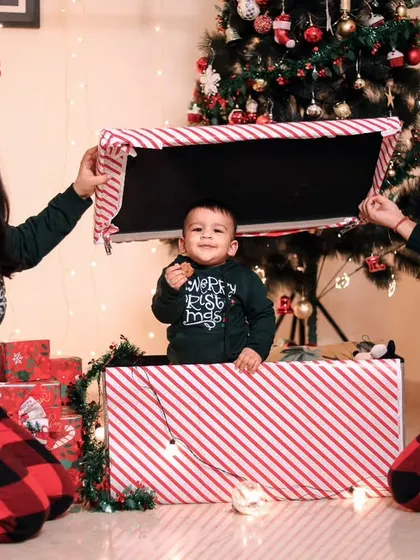 A fun and candid family moment during a Christmas shoot, with the baby popping out of a giant gift box.
