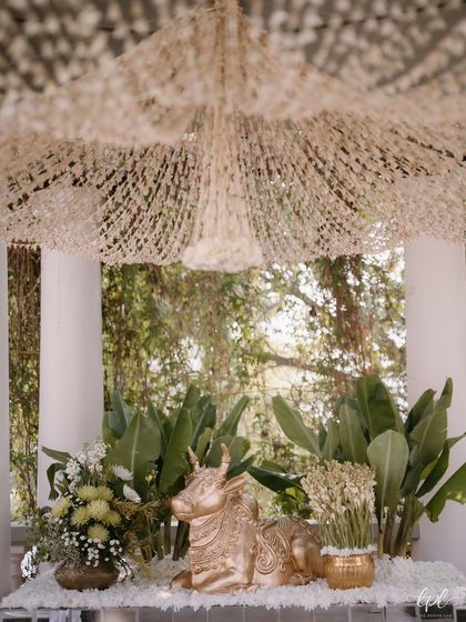 A golden Nandi statue sits among lush greenery and tuberose decor, adding a traditional and sacred element to this elegant green and white themed event.