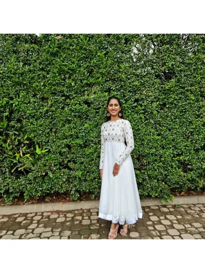A happy client in her custom white Anarkali. The bodice is intricately embroidered, flowing into a simple, elegant skirt, making it a versatile piece for any special occasion.