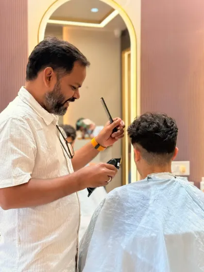 The finishing touches are key. Here, our stylist is perfecting the haircut with a comb and clipper, ensuring every detail is just right.