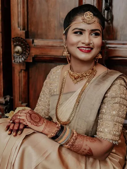 A beautiful bride seated against a traditional wooden backdrop, her simple mandala mehendi adding a touch of class.