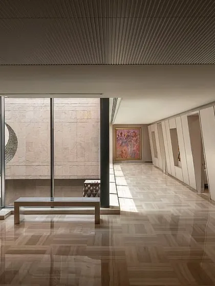 A long corridor on the directors' floor features wall niches for artwork and a large window overlooking the courtyard, blending circulation space with gallery-like moments.