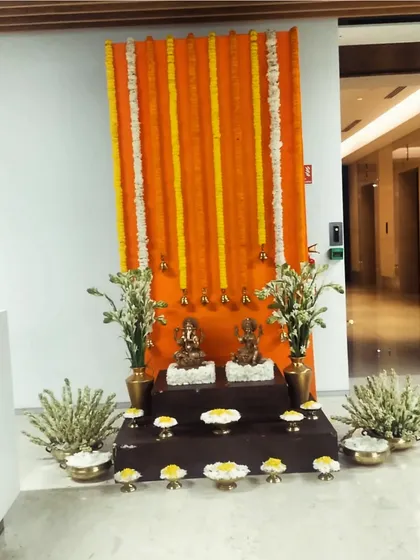 Another traditional setup for an office Diwali party. We created a backdrop of orange marigold garlands and placed idols on a tiered platform, surrounded by brass pots and fresh flowers.