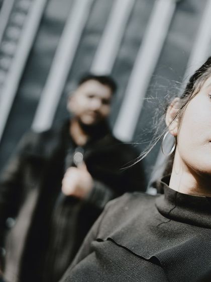 A creative portrait focusing on the bride's serene expression, with the groom blurred in the background.