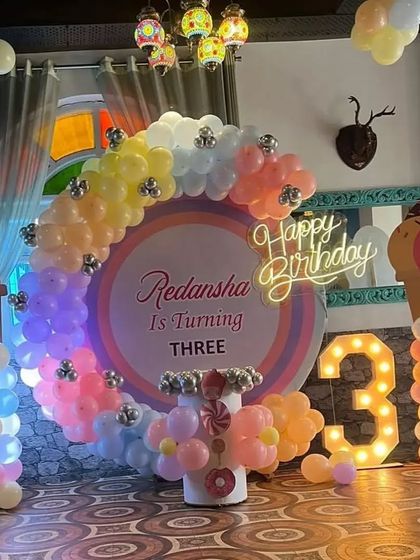 An ice cream-themed third birthday party, featuring a pastel balloon ring, ice cream cone props, and a light-up number '3'.
