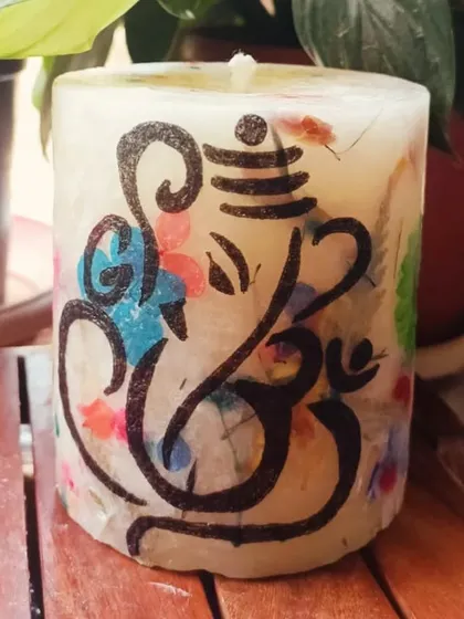 Celebrate Ganesh Chaturthi with our divine Ganesha Pillar Candle. This beautiful piece features a hand-drawn Ganesha design over a background of colorful pressed flowers.
