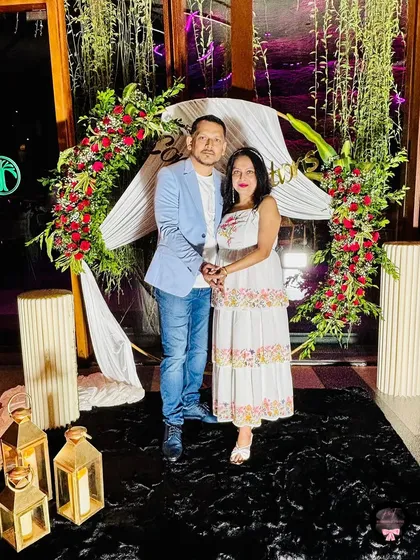 A happy client at a small send-off party we decorated. We created a lovely floral arch with red roses and white drapes for their photos.