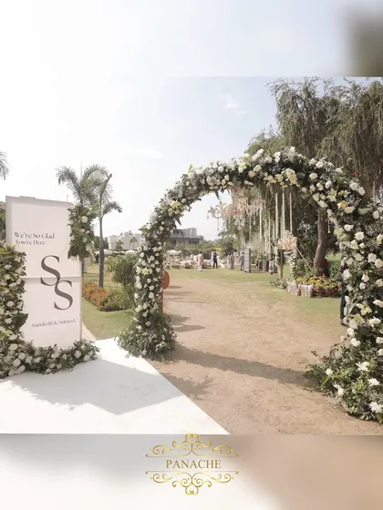 The main entrance to the wedding, featuring a welcome sign with the couple's monogram and a grand floral arch.