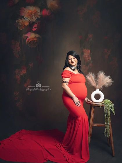 A fine art maternity photoshoot in a stunning red gown, presented in a classic and dramatic black and white edit.