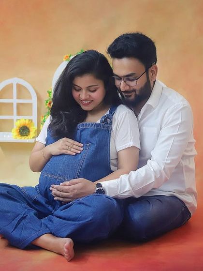A beautiful moment of connection as the couple looks down at the baby bump together. This casual studio shot is filled with love and anticipation.