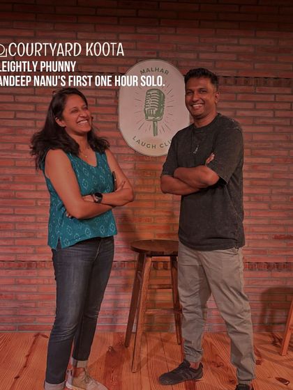 A candid shot of host Sreedevi Ajayan and comedian Sandeep Nanu sharing a laugh on stage. This captures the fun and camaraderie of the Malhar Laugh Club.