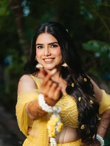 A cute and playful shot from her Haldi. The makeup is minimal and fresh, letting her natural happiness shine through.