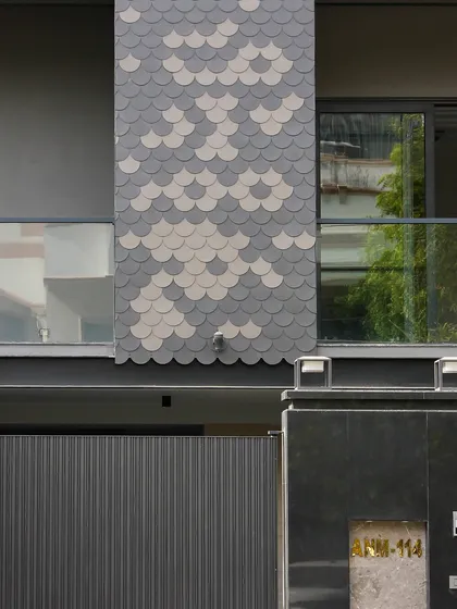 A close-up of the fish-scale tile pattern used on the Akashneem Marg project. This detail adds a unique, decorative element to the otherwise minimal and modern facade.