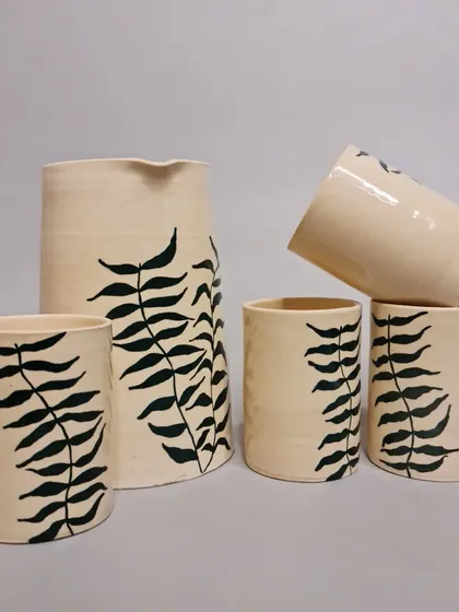 This handcrafted ceramic jug and glasses set is inspired by a delicate fern motif. Each piece is lovingly hand-painted, making it a work of art that is perfect for serving water or other beverages.
