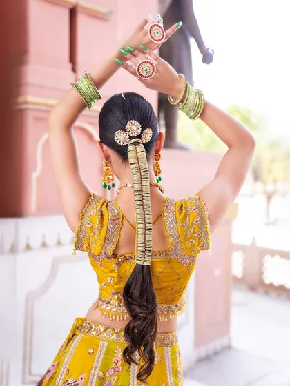A complete look is all about the details. This image shows how our accessories can complete your hairstyle, featuring a beautiful hair charm (parandi) that coordinates with the bride's modern AD jewellery and bangles.