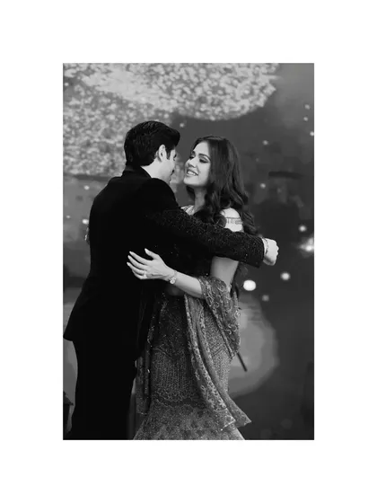 A timeless black and white photo of a couple sharing a slow dance. This image focuses on their gentle embrace and happy expressions, capturing a classic romantic moment.
