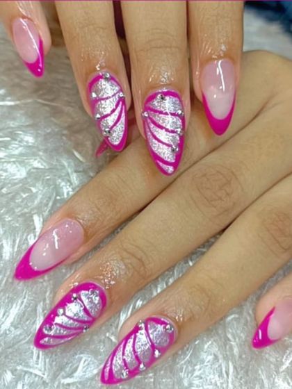 A vibrant and playful design featuring hot pink French tips and accent nails with a silver glitter wave pattern and rhinestones. This look is all about fun and glamour.