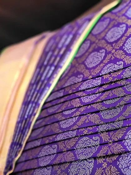 A soft-focus shot highlighting the sheen of the purple silk pleats.