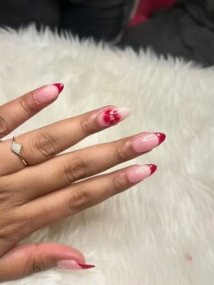 A close-up of a red blooming flower accent nail on a French manicure.