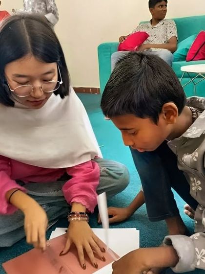 A volunteer from our Bangalore chapter helps a young boy with a craft activity. These one-on-one interactions are incredibly rewarding, building bonds of friendship and trust.