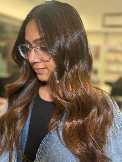 Effortless beauty, courtesy of balayage. This client is wearing a denim jacket that makes her warm hair tones pop.