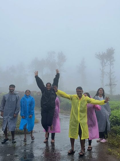 Friends jumping for joy in their raincoats on a wet day during the Bandaje trek.