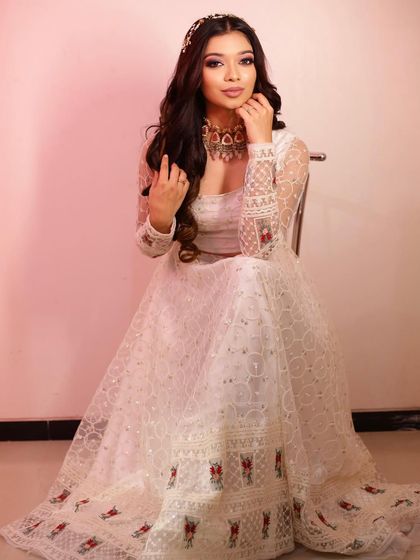 A full view of this elegant look. The open hairstyle adds a touch of modern romance to the traditional white lehenga.