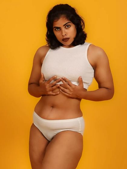 A bold and unapologetic portrait celebrating the female form. The simple white garments against a vibrant yellow background create a high-impact, minimalist statement.