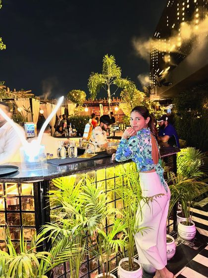 Leaning against the bar, this angle shows the backless detail of the floral bodysuit. It's a great way to add a surprising element to your outfit.