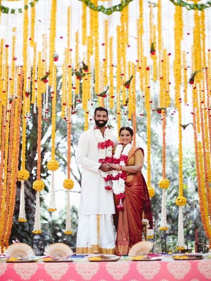 A stunning shot of the couple at their mandap, framed by beautiful yellow flower decorations. A perfect memory from a South Indian wedding.