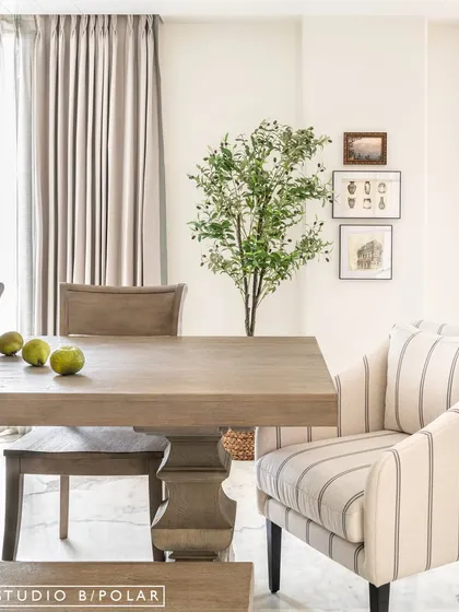 In the Sunlit Serenity dining room, we aimed for a light and airy feel. A solid wood pedestal table is paired with a mix of chairs and a bench, creating a relaxed yet elegant setting.