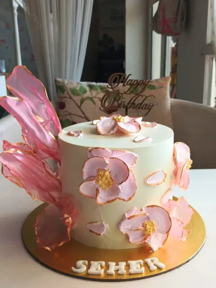 A minimalist and modern cake featuring abstract pink wafer paper sails and delicate, hand-painted flowers with gold edges.