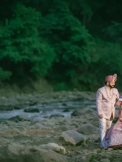 A majestic portrait of the couple against a backdrop of lush green mountains and a flowing river. This shot highlights the serene and grand beauty of a destination shoot in Rishikesh.