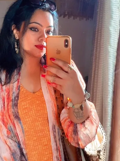 A mirror selfie capturing the details: red nails, a statement bracelet, and delicate earrings that complete the look.