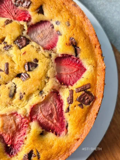 A close-up shot of the tea-time cake, showing the beautiful texture of the baked strawberries and melted chocolate chunks within the golden-brown crumb.