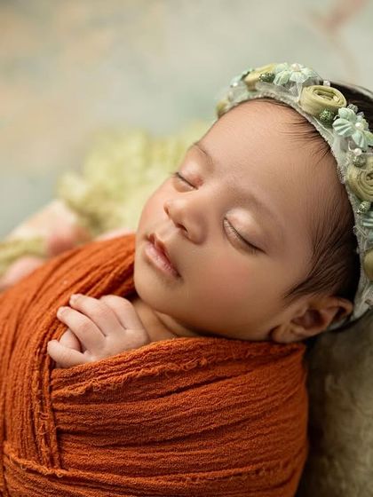 A close up on the baby's face from the painterly backdrop session, highlighting her delicate features and the beautiful floral headband that complements the scene.