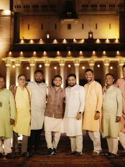 The groom and his friends, the 'Jodhpur Jodhas', posing in front of a beautifully lit palace. This shows the fun and camaraderie of a destination wedding.