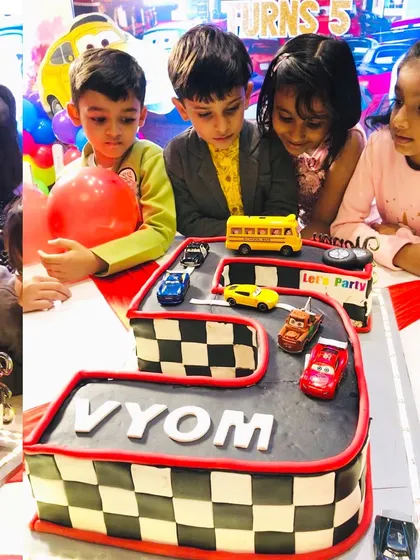 The birthday boy and his friends excitedly gathered around the number 5 racing track cake.