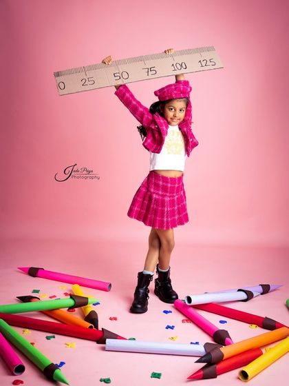 Holding up a giant ruler, this shot adds a fun, graphic element to the 'Back to School' theme. The props are designed to be lightweight and safe for kids to handle.