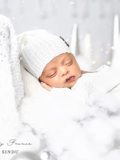 A close-up of a little snowflake, sleeping peacefully amidst a dreamy, white winter setup. My priority is always your baby's comfort and safety during these delicate sessions.