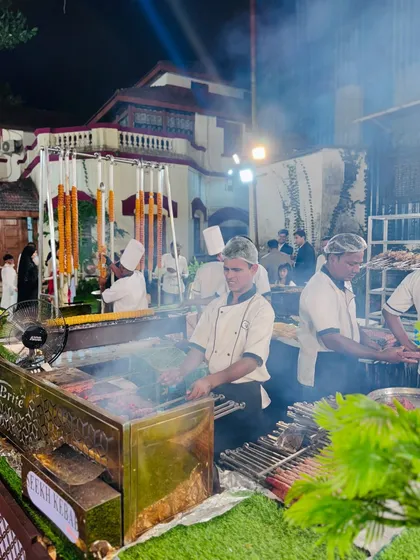 The barbecue station is a hub of activity, with chefs preparing Seekh Kebabs and other grilled items in a smoky, aromatic setting.