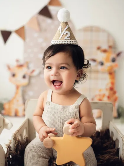A baby celebrates his half-birthday with a cute hat and a giraffe-themed setup. Milestone photoshoots aren't just for the first birthday!