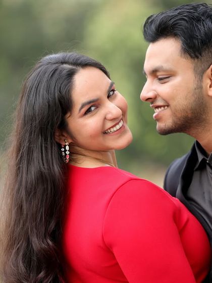 A close-up, candid shot of a couple sharing a happy, intimate moment. The woman's bright smile towards the camera makes this a warm and engaging pre-wedding portrait.