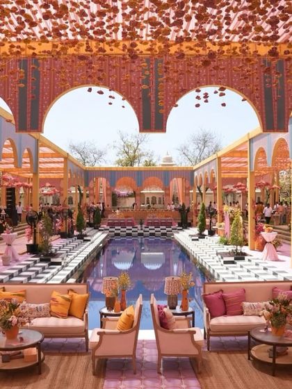 A spectacular poolside haldi setup that feels like stepping into a royal Rajasthani palace. The intricate arches, checkered floor, and abundance of warm-toned florals create an atmosphere of pure opulence.