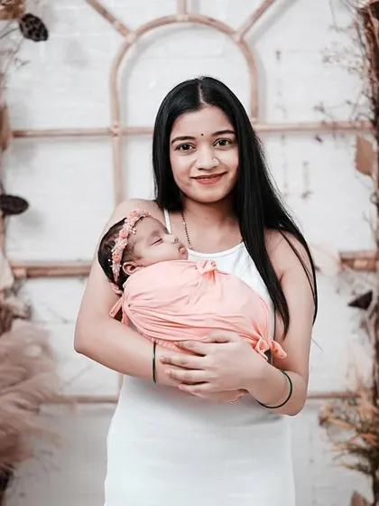 A mother's gentle embrace. She smiles warmly while holding her sleeping baby girl, creating a beautiful and loving portrait.