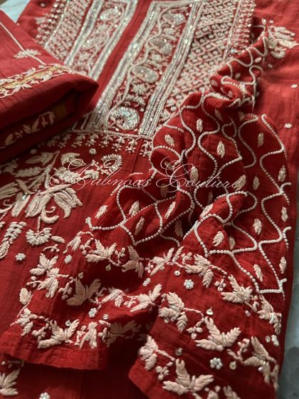 This image focuses on the sleeve and side panel of the red Anarkali, showing the continuity of the intricate embroidery and the quality of the Mul fabric.