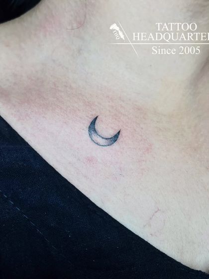 A small, shaded crescent moon tattoo on the collarbone, a simple and elegant choice.