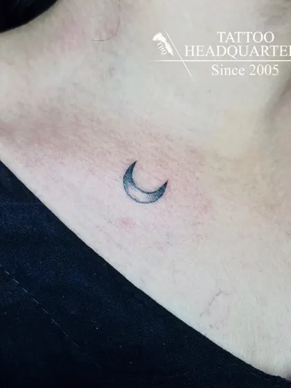 A small, shaded crescent moon tattoo on the collarbone, a simple and elegant choice.