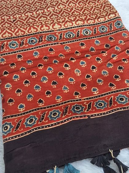 A stunning Ajrakh print fabric with a mix of floral and geometric patterns. The earthy red and blue tones are characteristic of this traditional craft.